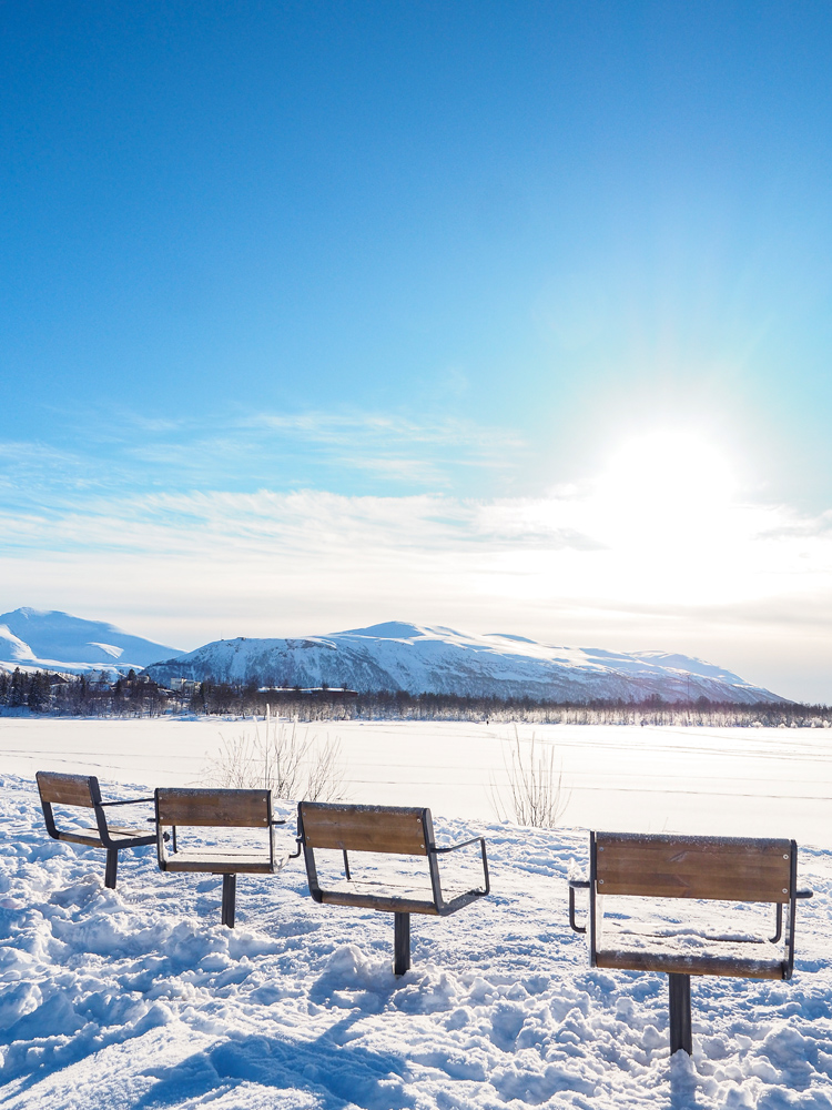 Stühle am verschneiten See Prestvannet in Tromsö im Winter