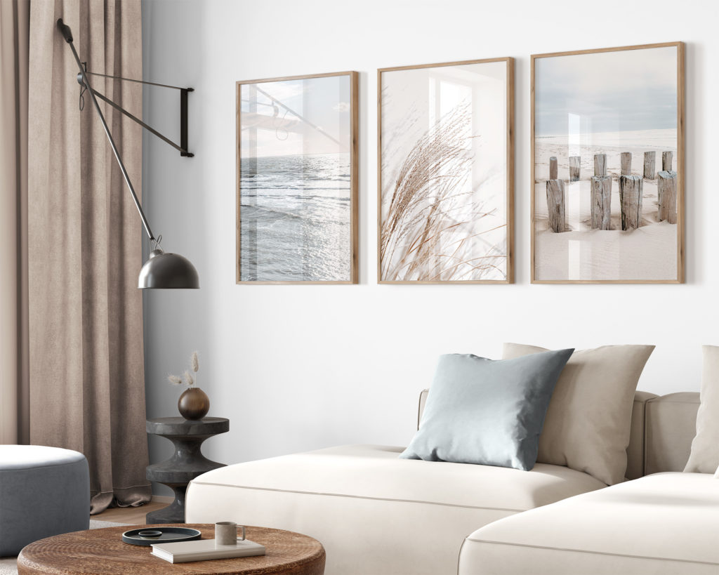 Drei große Poster in harmonischem Look in vertikaler Anordnung über Sofa arrangiert