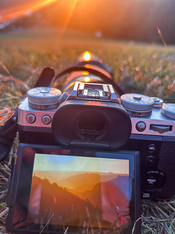 Kamera liegt im Gras und zeigt auf dem Display den Sonnenuntergang im Sauerland