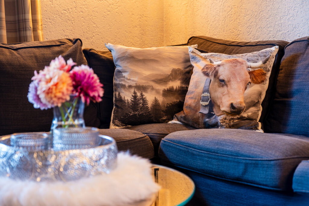 Dunkles Sofa mit gemusterten Kissen und Blumen im Wohnbereich