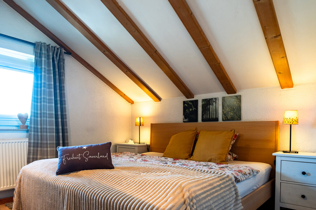 Schlafzimmer mit Holzbalken und gemütlichem Doppelbett in der Unterkunft