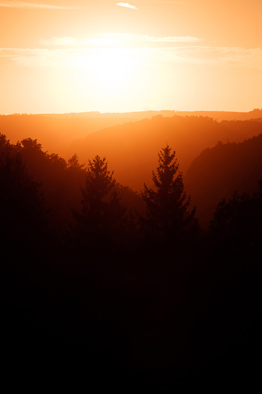 Sonne geht hinter mehreren bewaldeten Hügelketten des Sauerlands unter