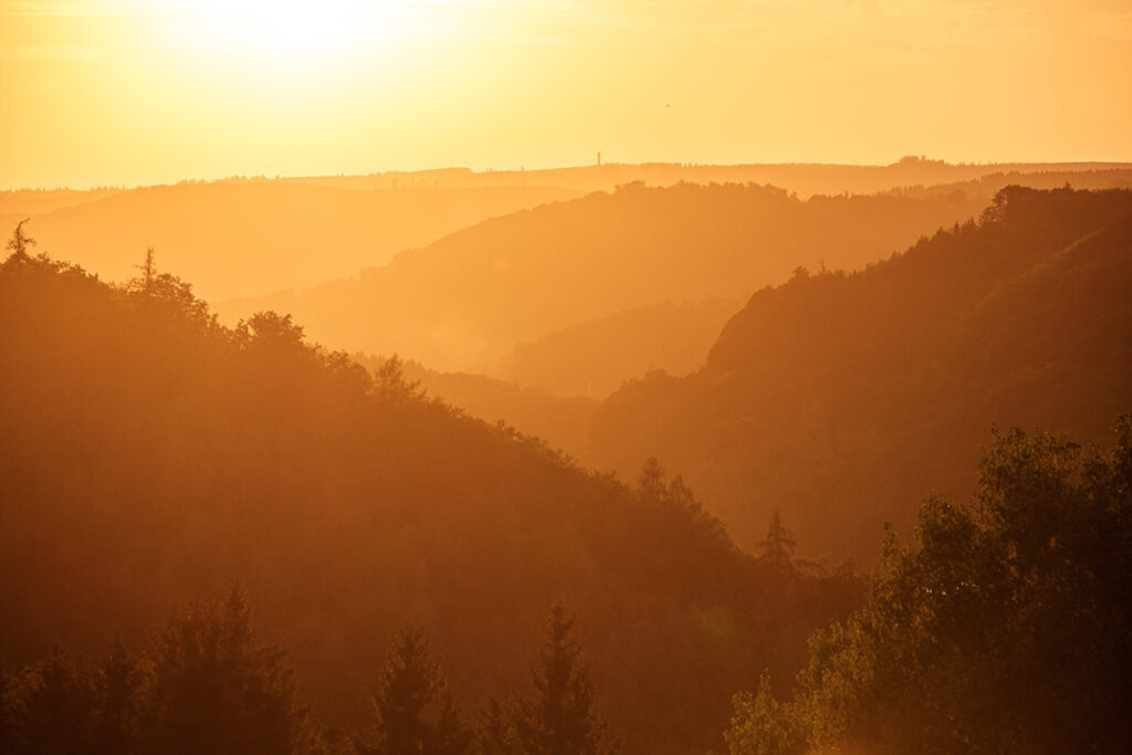 Sonne geht hinter mehreren bewaldeten Hügelketten des Sauerlands unter